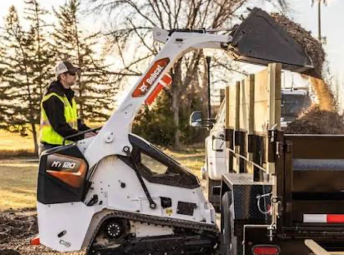 Bobcat skid steer loading material into a dump trailer