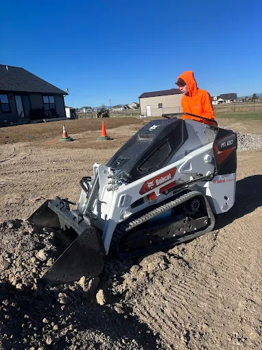 CAT skid steer with mulching attachment in front of Montana mountains